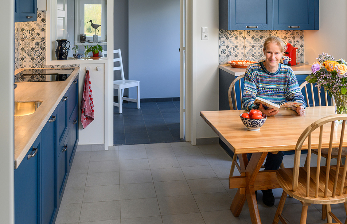 Blauwe keuken met klassieke tegels als achterwand, houten werkblad, moderne apparatuur en decoratieve elementen.