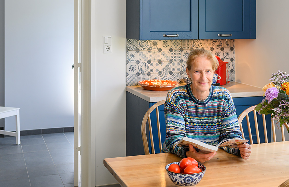 Blauwe keuken met klassieke tegels als achterwand, houten werkblad, moderne apparatuur en decoratieve elementen.