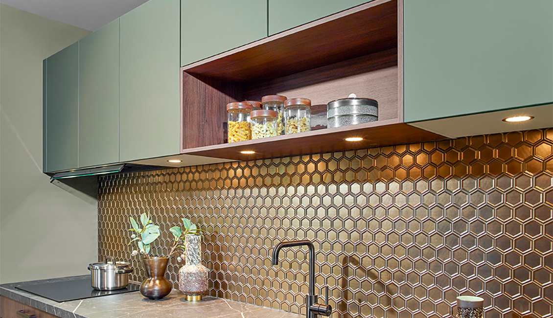 Moderne keuken met houtlook onderkasten, groene bovenkasten en een hexagonale mozaïek achterwand.