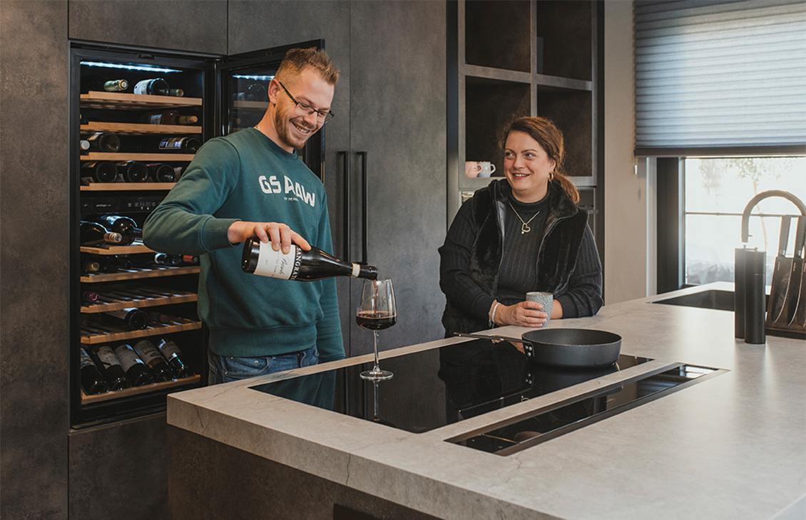 Moderne keuken met keukeneiland, barkrukken en ingebouwde wijnkoeler.